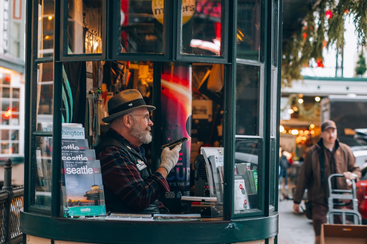 service-01 Man in Seattle's iconic visitor booth offering tourist information and brochures.