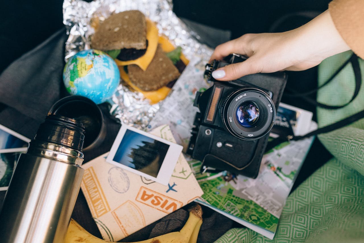 about-03 Capture memories with a vintage camera amid travel essentials like a map, snacks, and polaroid photos.
